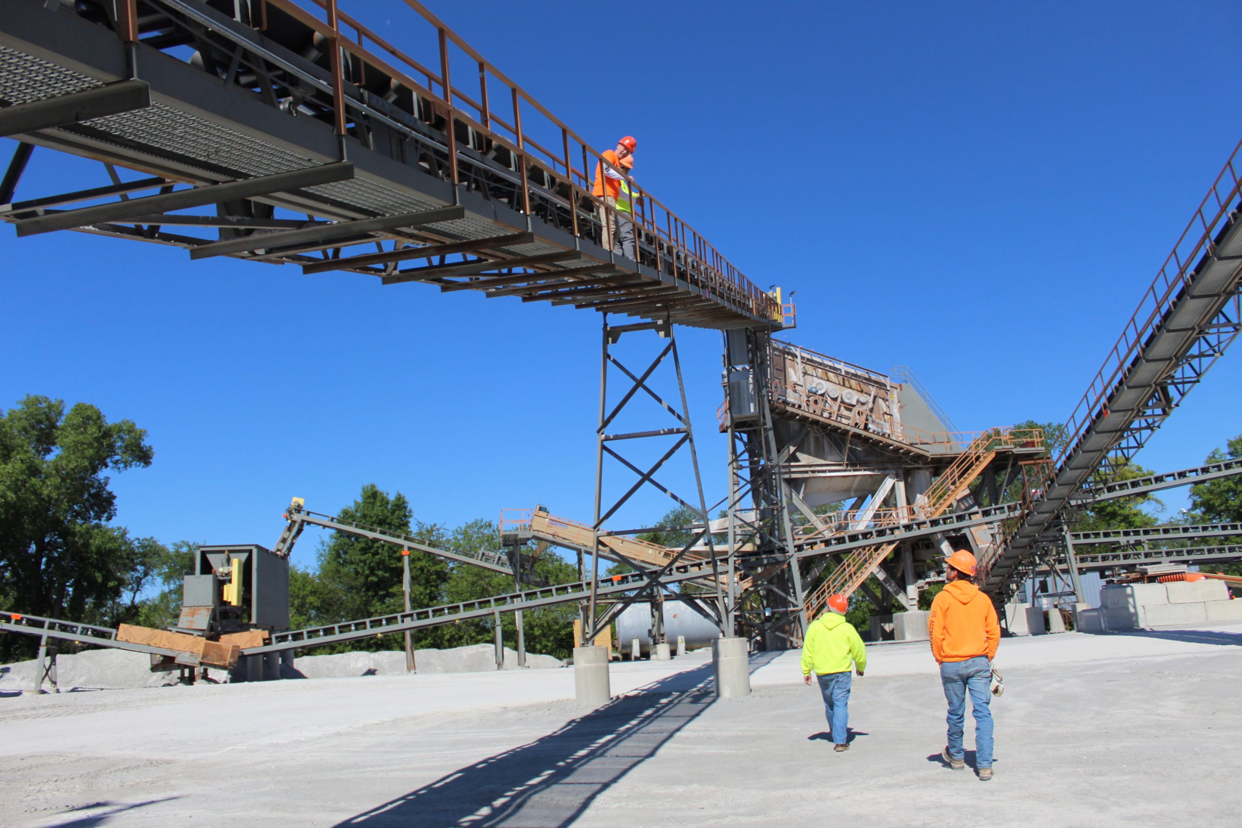 two employees inspecting an elevated catwalk and two more walking under it